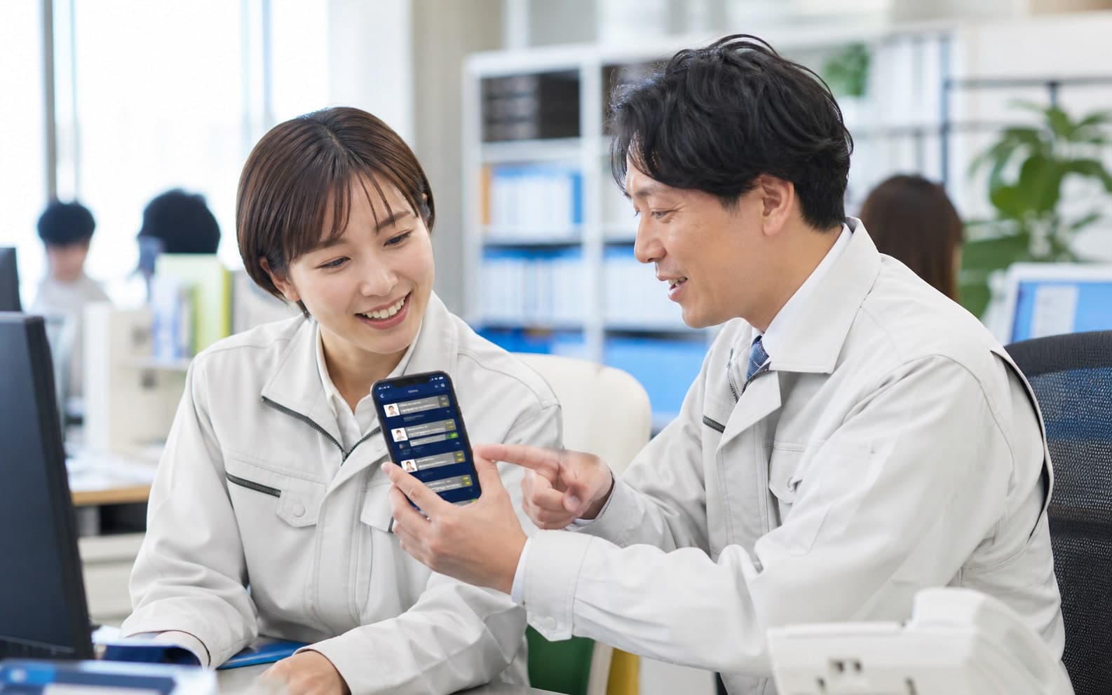 スタッフがスマートフォンで社内の情報を共有するイメージ